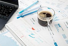 Eine Kaffeetasse steht auf Aktien-Unterlagen - Foto: Christin Klose/dpa-tmn