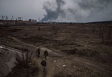 Soldaten gehen einen Weg entlang, während Rauch in Irpin nordwestlich von Kiew aufsteigt. - Felipe Dana/AP/dpa