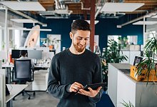 Mann mit Tablet in einem Großraumbüro - Zacharie Scheurer/dpa-tmn