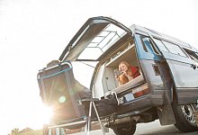 Frau schaut aus dem Campingbus - Christin Klose/dpa-tmn