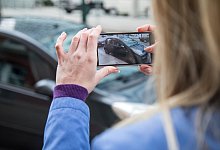 Frau fotografiert ein Auto - Christin Klose/dpa-tmn