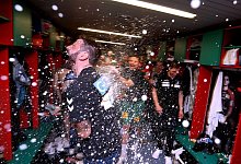 Der Magdeburger Trainer Bennet Wiegert wird in der Mannschaftskabine mit Sekt bespritzt. - Ronny Hartmann/dpa