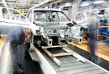 Mitarbeiter montieren Kotflügel an einem Auto - Julian Stratenschulte/dpa/dpa-tmn