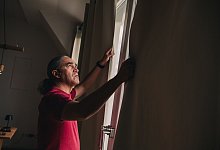 Gardinen schliessenEin Mann zieht Vorhänge zu - Zacharie Scheurer/dpa-tmn