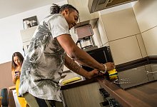 Ein Mann putzt und eine Frau schaut auf ihr Handy - Christin Klose/dpa Themendienst/dpa-tmn