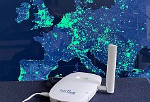 Ein Funk-Hotspot des Helium-Netzwerks vor einer Karte der Netzabdeckung in Europa. - Christoph Dernbach/dpa