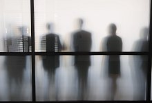 Personen stehen hinter eine Glasscheibe in einem B&uuml;ro - Sebastian Kahnert/dpa/dpa-tmn