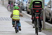 Ein Kind fährt mit dem Rad auf dem Fußweg neben einem Elternteil - Jan Woitas/dpa/dpa-tmn