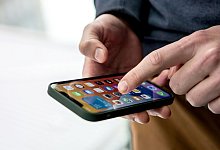 Ein Mann bedient ein iPhone - Foto: Zacharie Scheurer/dpa-tmn