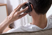 Ein Mann sitzt telefonierend auf der Couch. - Foto: Christin Klose/dpa-tmn