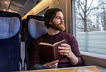 Ein Mann liest ein Buch in einem Zug - Christin Klose/dpa-tmn