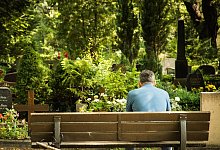 Ein Mann sitzt auf einer Friedhofsbank - Christin Klose/dpa-tmn