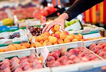 Ein Mann greift auf einem Wochenmarkt in eine Kiste Aprikosen - Hauke-Christian Dittrich/dpa/dpa-tmn