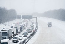 LKW und Autos stehen bei Schnee im Stau - Fabian Strauch/dpa/dpa-tmn