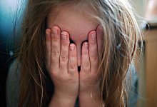 Schutz: Ein junges Mädchen hält sich die Hände vor ihr Gesicht.  - Nicolas Armer/dpa