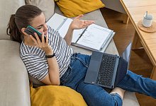 Eine Person am Handy vor einem Notebook - Christin Klose/dpa-tmn