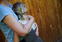 Ein M&auml;dchen wird von seiner Mutter in den Arm genommen - Annette Riedl/dpa/dpa-tmn