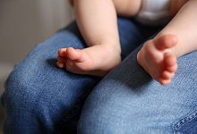 Baby sitzt auf dem Schoß einer Frau - Mascha Brichta/dpa-tmn