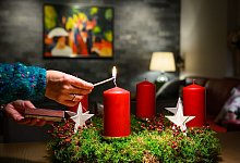 Eine Frau z&uuml;ndet eine Kerze auf einem Adventskranz an - Patrick Pleul/dpa/dpa-tmn