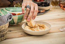 Ein Mann dippt ein Stück Brot in Hummus - Christin Klose/dpa-tmn