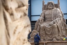 Ein Mann arbeitet an einer Sandskulptur des G&ouml;ttervaters Zeus auf seinem Thron. - Stefan Sauer/dpa