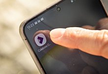 Mann benutzt Smartphone-App Collabora Office - Christin Klose/dpa-tmn