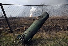 Der Teil einer Rakete liegt auf dem Boden vor einem brennenden Munitionslager in der N&auml;he der ostukrainischen Stadt Balaklija (Ukraine). - Mykhailo Andriiv/AP/dpa