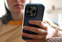 Eine junge Frau sitzt mit ihrem Smartphone auf dem Sofa - Elisa Schu/dpa/dpa-tmn