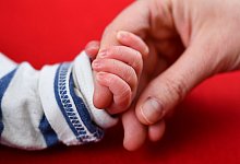 Mutter und Neugeborenes halten H&auml;nde - Foto: Uwe Anspach/dpa-tmn