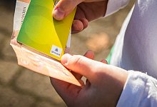 Junge hält Girokarte und Geldschein in den Händen - picture alliance/dpa/dpa-tmn