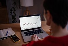 Rearview woman wok on laptop with crypto charts. Investor online tracking digital currency rates - picture alliance / Zoonar