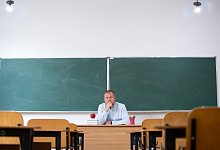 Teacher in empty classroom, Exhausted teacher in the classroom in fron of the blackboard. Back to sc - IMAGO/Panthermedia