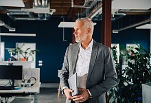 Ein Mann trägt ein Notebook in den Händen - Zacharie Scheurer/dpa-tmn