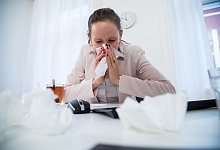 Frau putzt sich am Computer die Nase - Christin Klose/dpa-tmn