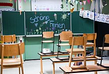 Hochgestellte Stühle und eine bemalte Tafel am letzten Schultag - Jens Kalaene/dpa