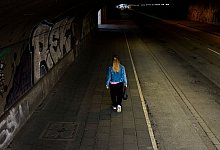 Frau läuft am Abend durch einen Tunnel mit geringer Beleuchtung - Christoph Reichwein/dpa