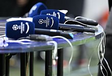 Mikrofone mit dem Logo der Champions League liegen vor einem Spiel auf einem Tisch. - Angelika Warmuth/dpa