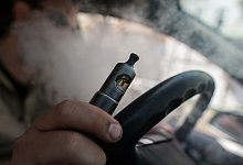 Ein Mann raucht eine E-Zigarette im Auto - Franziska Gabbert/dpa-tmn