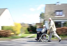 Ein Mann schiebt eine Frau im Rollstuhl - Mascha Brichta/dpa-tmn