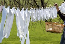 Weiße Wäsche wird zum Trocknen im Garten aufgehangen - Roland Weihrauch/dpa/dpa-tmn