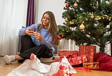 Eine Frau packt ein Weihnachtsgeschenk aus - Christin Klose/dpa-tmn