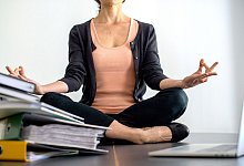 Eine Frau sitzt im Schneidersitz auf einem Schreibtisch - Klaus-Dietmar Gabbert/dpa-tmn