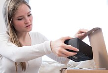 Eine Frau öffnet ein Paket - Christin Klose/dpa-tmn