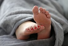 F&uuml;&szlig;e schauen unter einer Decke hervor - Roland Weihrauch/dpa/dpa-tmn