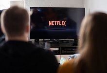 Paar sitzt vor Fernseher, auf dem das Netflix-Logo zu sehen ist - Daniel Reinhardt/dpa/dpa-tmn