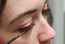 Eine Frau tr&auml;gt roten Eyeliner auf - Julia Bresching/dpa-tmn