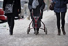Ein Frau geht mit Rollator auf einem schneebedeckten Gehweg - Paul Zinken/dpa/dpa-tmn