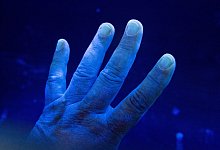 Desinfizierte Hand wird unter eine UV-Lampe gehalten - Daniel Reinhardt/dpa/dpa-tmn