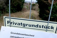 Ein Grundsteuerbescheid vor einem Privatgrundstück - Bernd Weißbrod/dpa/dpa-tmn
