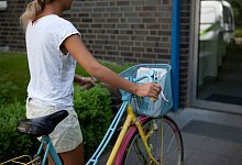 Ein M&auml;dchen tr&auml;gt Zeitungen aus - Silvia Marks/dpa-tmn